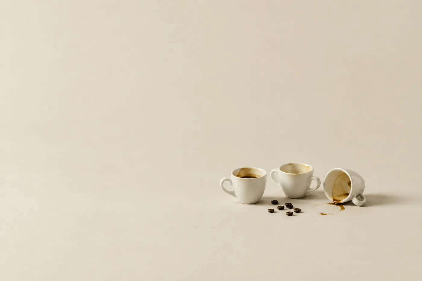 Three used espresso cups in a row, one tipped over