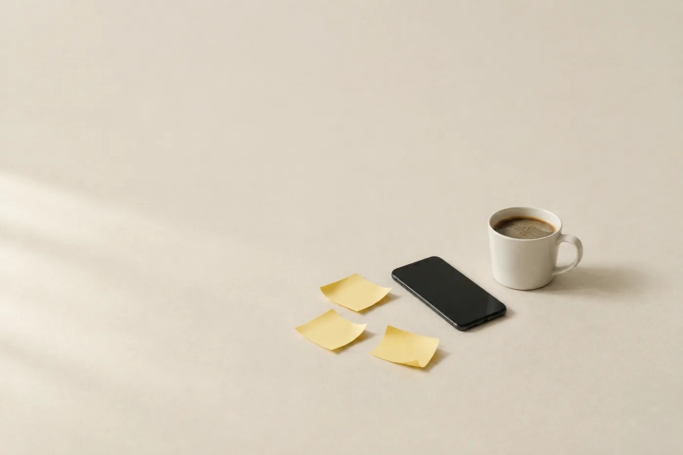 Curled sticky notes, a phone face up and a cold cup of coffee