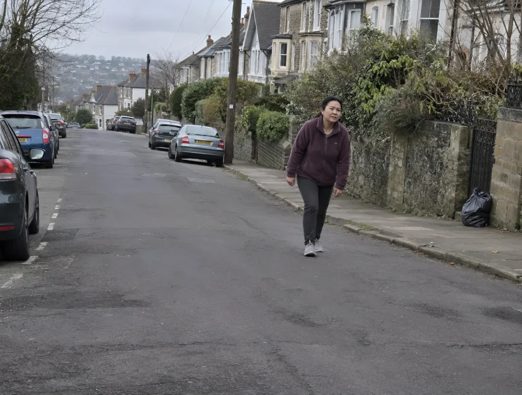 A woman walking up a neighbourhood hill on an overcast morning